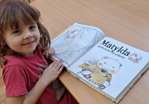 Dziewczynka ogląda książkę o niedźwiedziach polarnych.